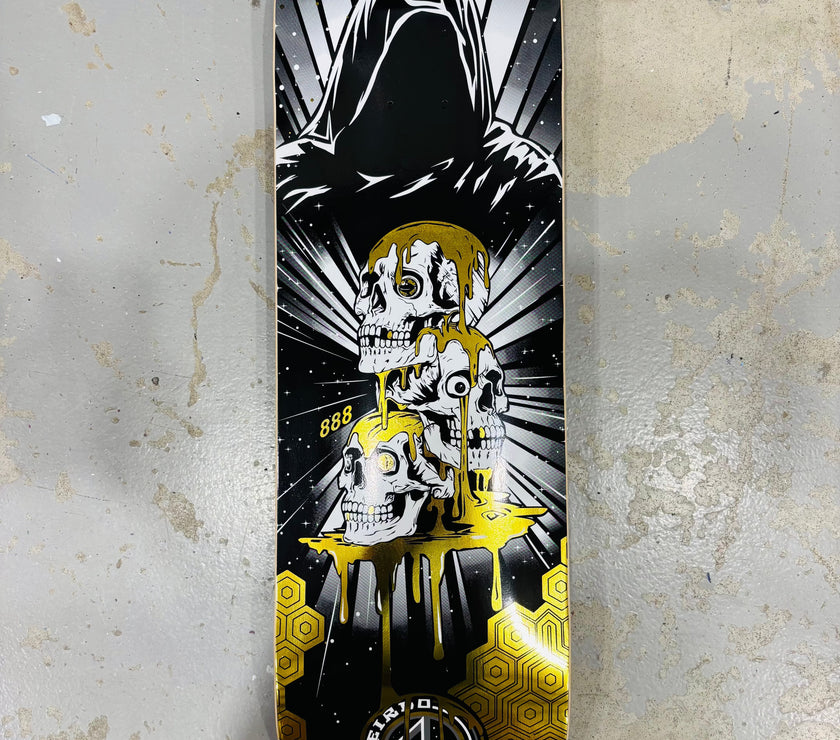 “Grim Skull” Skateboard by artist 888.  The skateboard is laying on the floor of the manufacturing plant