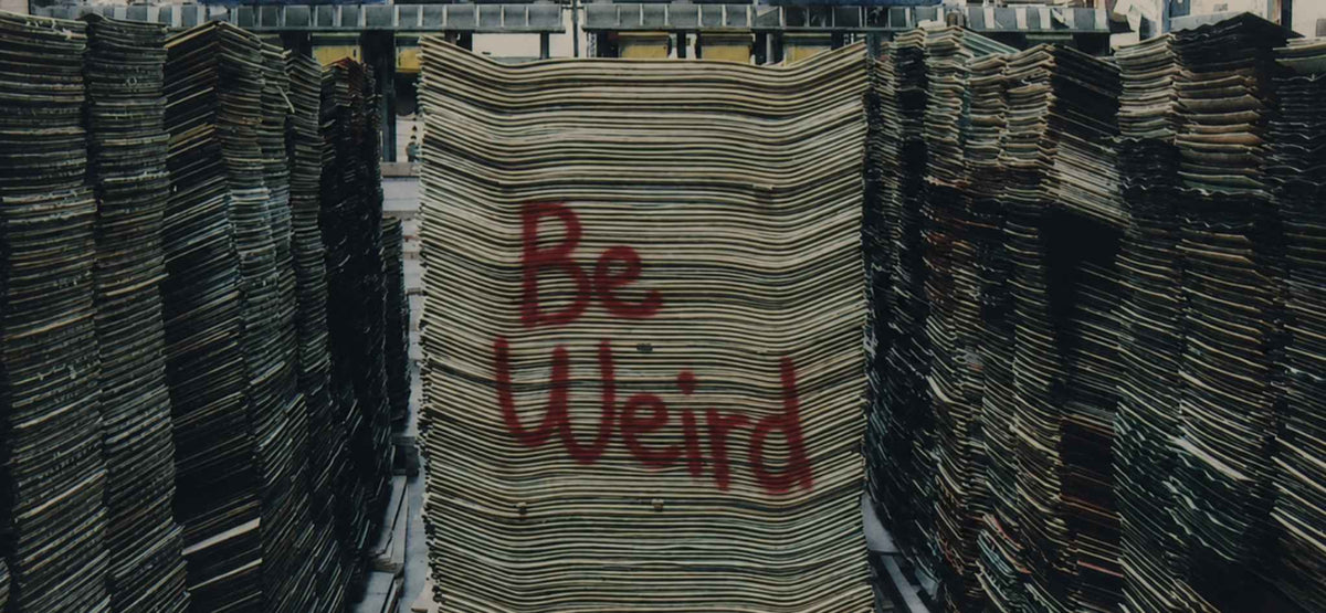 Big stacks of skateboard decks and "be weird" lettering