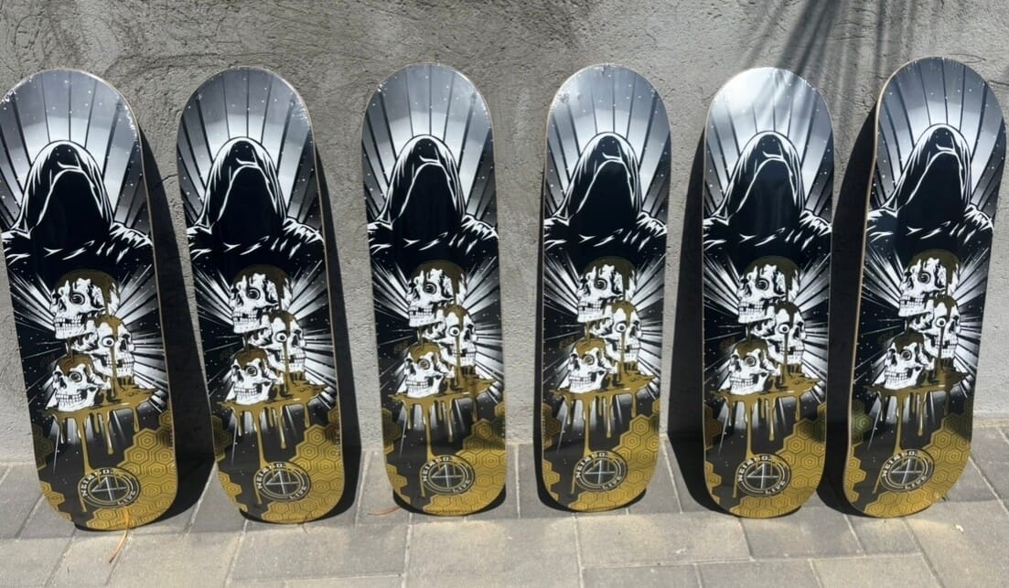 Six skateboard decks with a black and white design on a concrete floor.